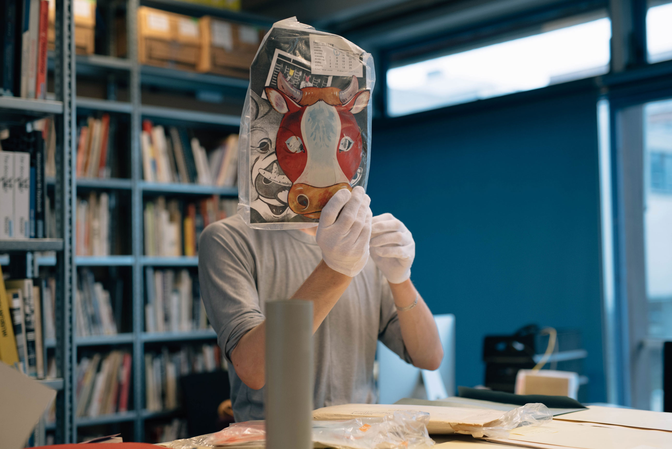 Artist Jan Huskes holding a mask at De Appel's Archive, part of the project Landscape with Bear, curated by the De Appel Curatorial Programme.