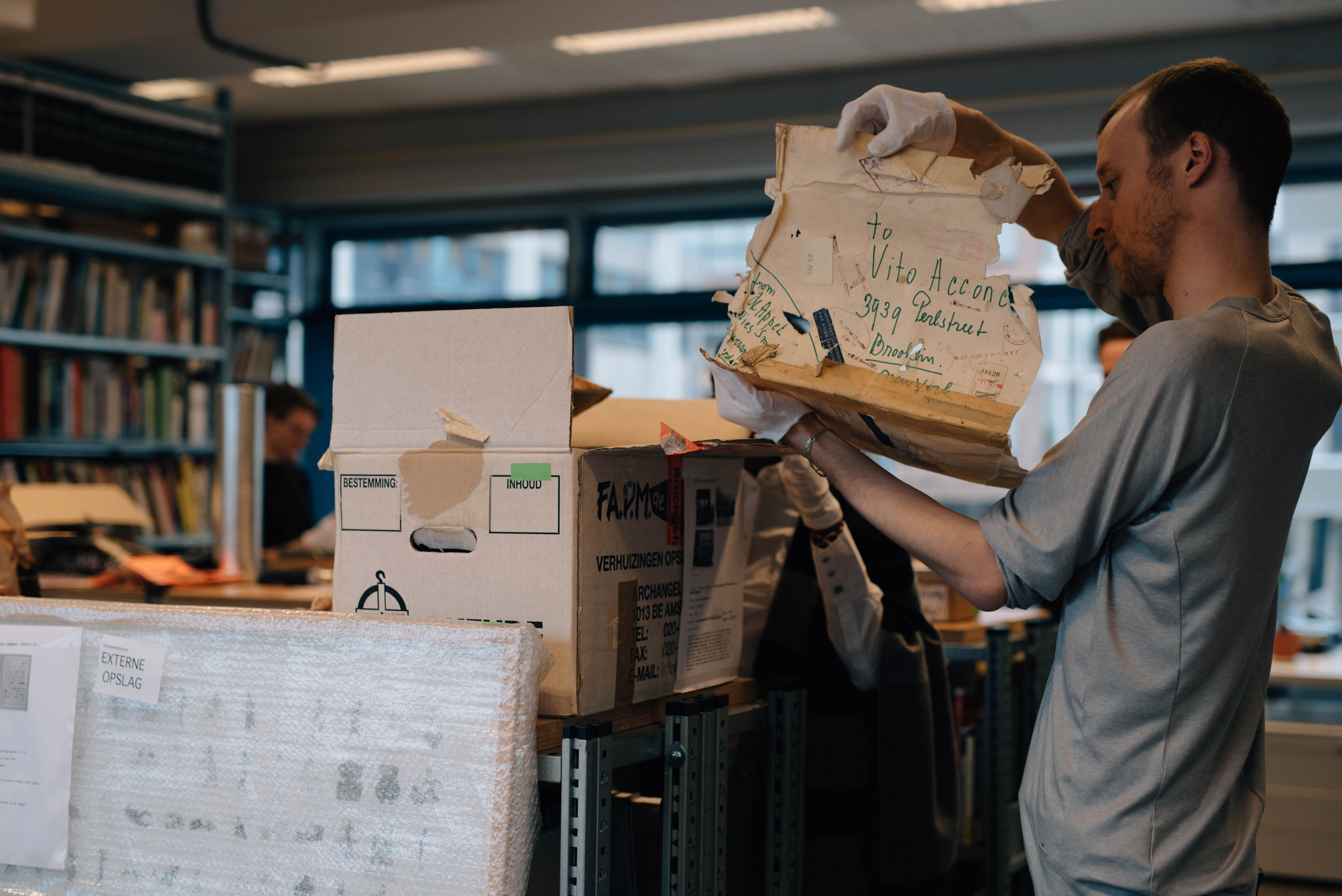 Artist Jan Huskes holding a document sent by Vito Acconci at De Appel's Archive, part of the project Landscape with Bear, curated by the De Appel Curatorial Programme.
