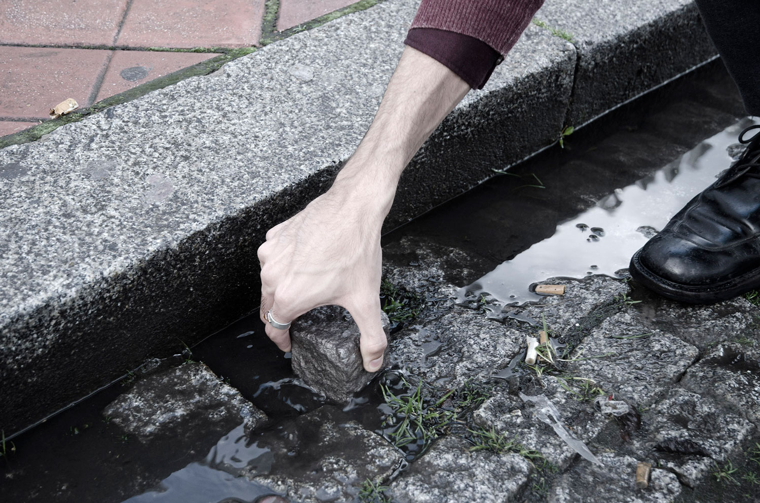 Daniel de Paula extracting a cobblestone outside the Gare de Calais-Ville, Calais, France
